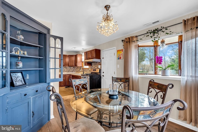 dining space with light hardwood / wood-style floors, sink, and a chandelier