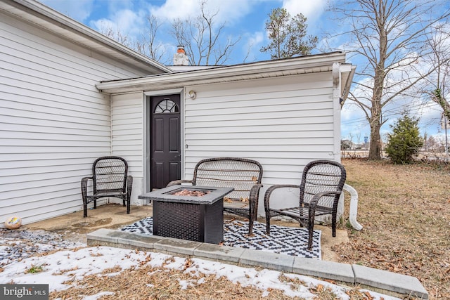 snow covered patio with an outdoor fire pit