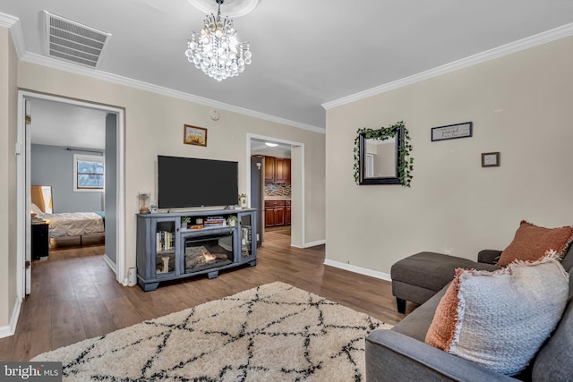 living room featuring a notable chandelier, hardwood / wood-style floors, and crown molding