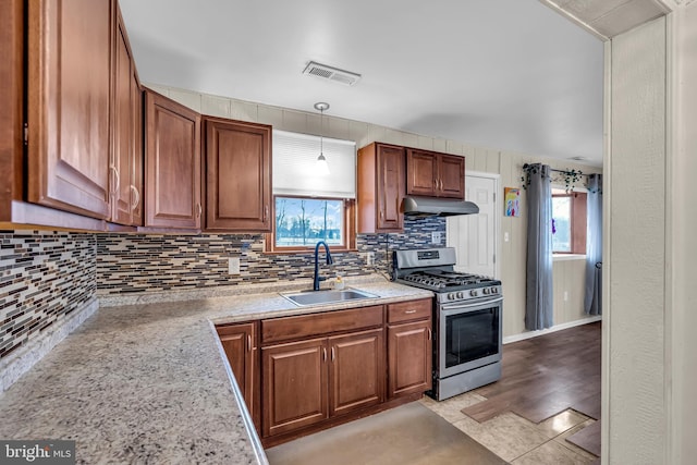 kitchen featuring sink, stainless steel gas stove, a wealth of natural light, and light tile patterned floors