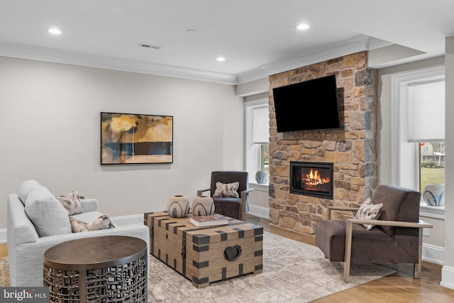 living room with ornamental molding, a fireplace, and light wood-type flooring