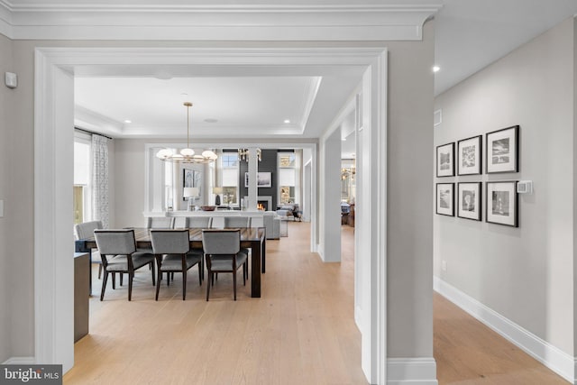 dining room with a tray ceiling, light hardwood / wood-style flooring, and a notable chandelier