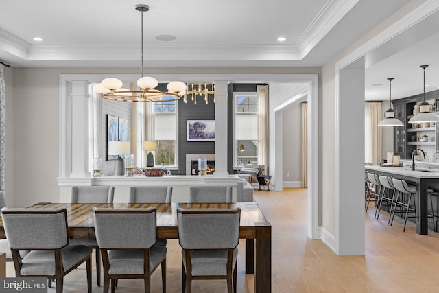 dining area with crown molding, a tray ceiling, and light hardwood / wood-style floors