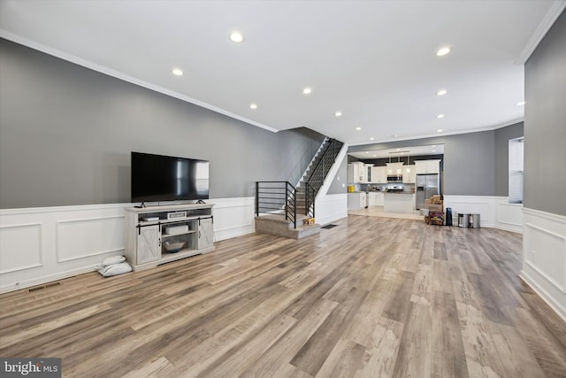 living room with light wood finished floors, wainscoting, stairs, crown molding, and recessed lighting