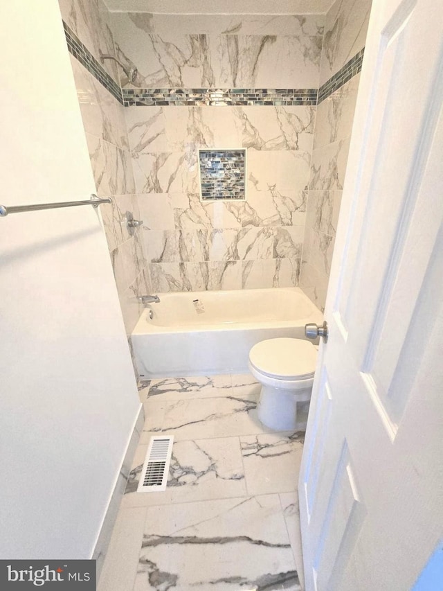 bathroom featuring tiled shower / bath combo and toilet