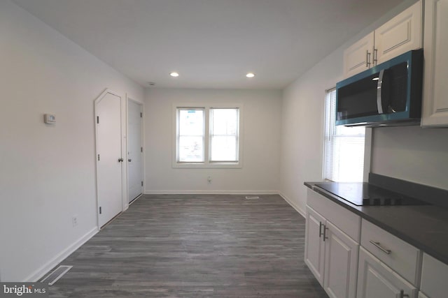 kitchen with white cabinetry, black electric stovetop, and dark hardwood / wood-style flooring