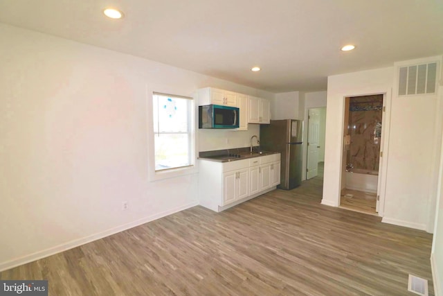 kitchen with stainless steel refrigerator, wood-type flooring, sink, and white cabinets