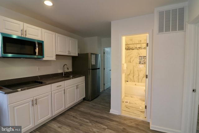 kitchen featuring white cabinetry, sink, black electric stovetop, and stainless steel refrigerator