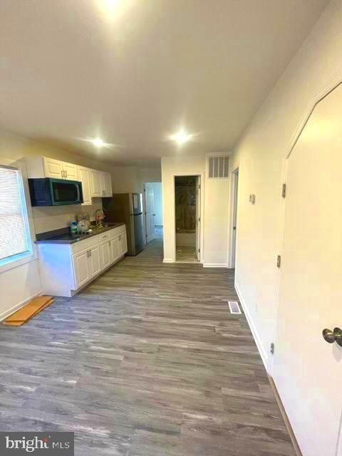 kitchen featuring dark hardwood / wood-style floors, sink, white cabinets, and stainless steel refrigerator