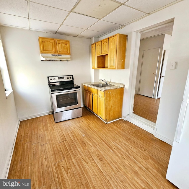 kitchen with sink, a drop ceiling, stainless steel range with electric stovetop, and light wood-type flooring