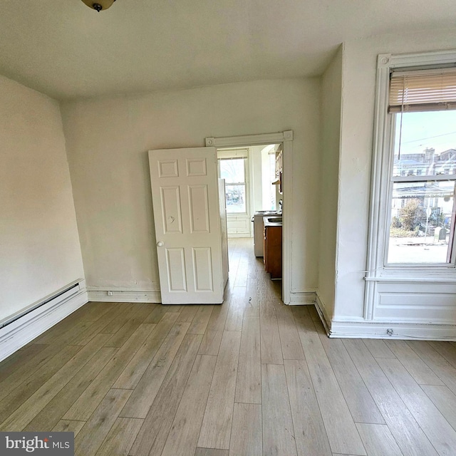 unfurnished room with a baseboard radiator and light hardwood / wood-style flooring