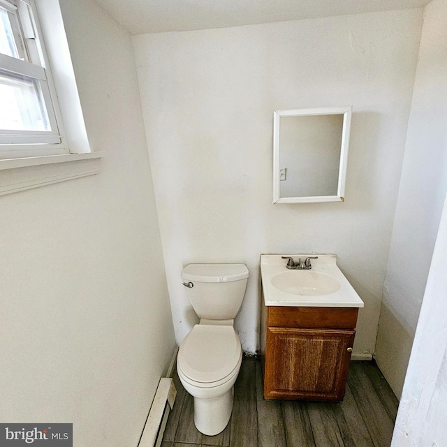 bathroom with baseboard heating, vanity, wood-type flooring, and toilet