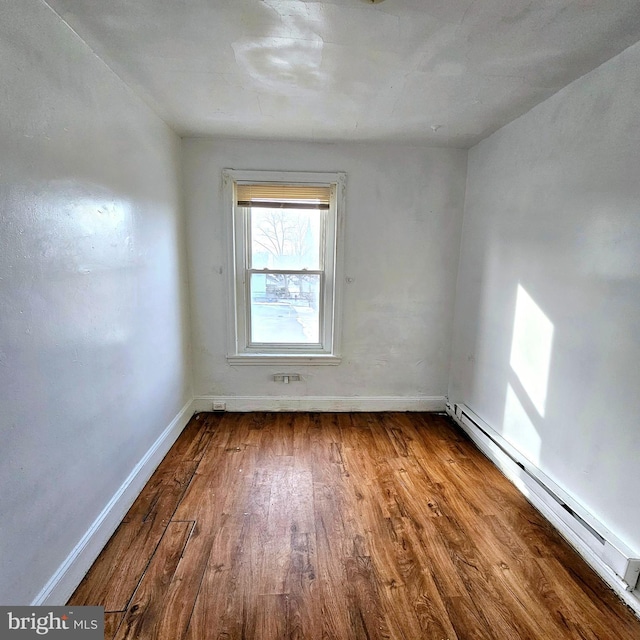 empty room featuring hardwood / wood-style floors and a baseboard heating unit