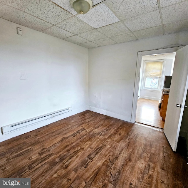 spare room with hardwood / wood-style flooring, a drop ceiling, and a baseboard heating unit