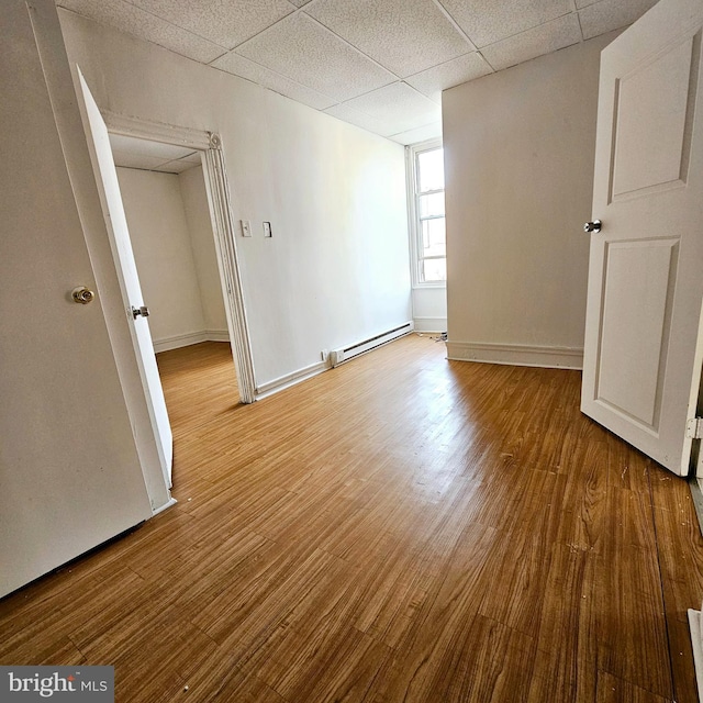 spare room featuring a paneled ceiling, light hardwood / wood-style flooring, and baseboard heating