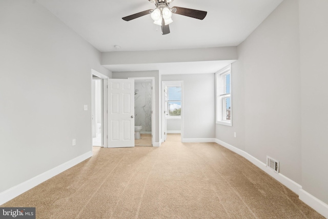 unfurnished bedroom featuring ceiling fan, light carpet, and connected bathroom