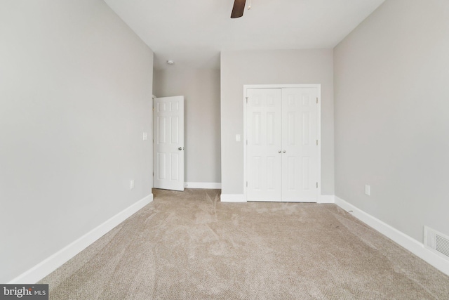 unfurnished bedroom featuring light carpet, a closet, and ceiling fan