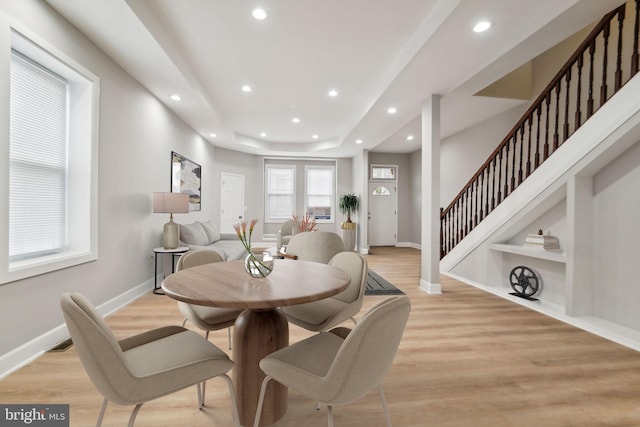 dining room featuring built in shelves, light hardwood / wood-style floors, and a tray ceiling