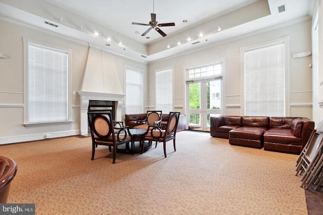 living room featuring a raised ceiling, ornamental molding, and a large fireplace