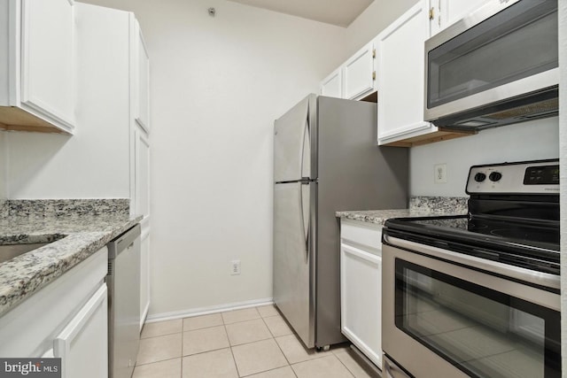 kitchen featuring light tile patterned flooring, stainless steel appliances, light stone countertops, and white cabinets