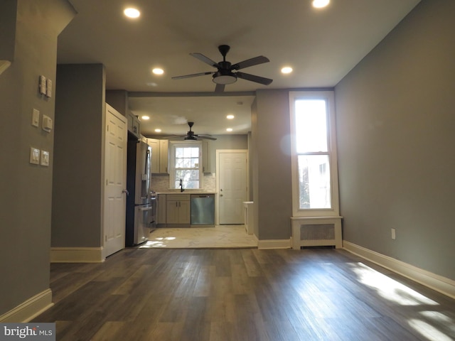 unfurnished living room featuring ceiling fan, sink, and dark wood-type flooring