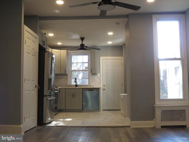 kitchen featuring radiator, ceiling fan, dark wood-type flooring, stainless steel appliances, and tasteful backsplash