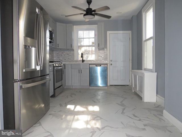 kitchen with gray cabinetry, ceiling fan, stainless steel appliances, and tasteful backsplash