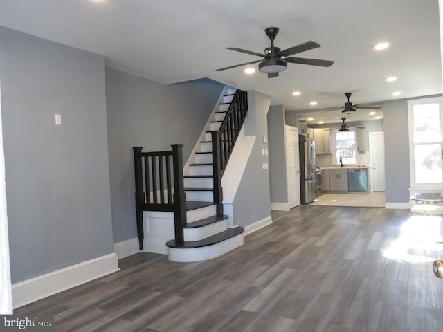 unfurnished living room with ceiling fan, sink, and dark wood-type flooring