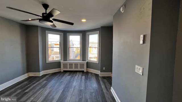 spare room featuring ceiling fan, radiator heating unit, and dark hardwood / wood-style floors