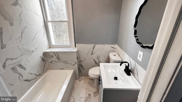 bathroom with vanity, toilet, tile walls, and a tub