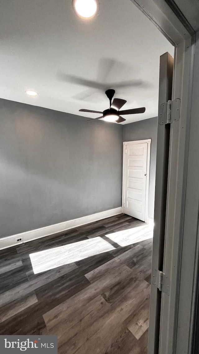 empty room with ceiling fan and dark wood-type flooring