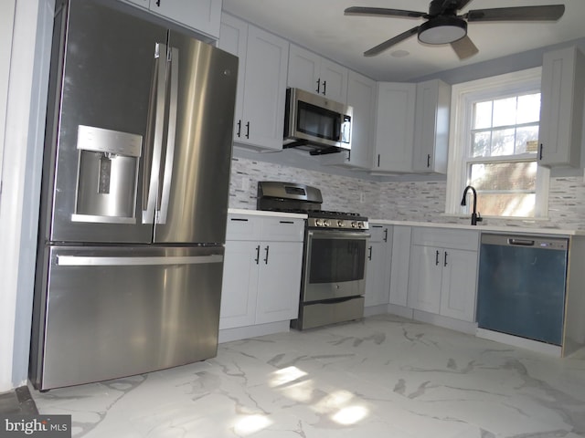 kitchen with ceiling fan, sink, stainless steel appliances, tasteful backsplash, and white cabinets