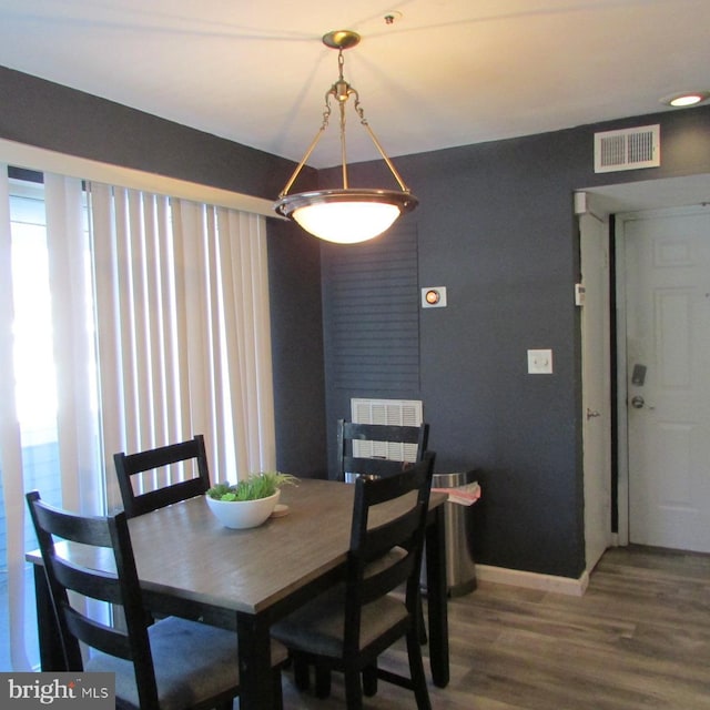 dining space featuring visible vents, a fireplace, baseboards, and wood finished floors