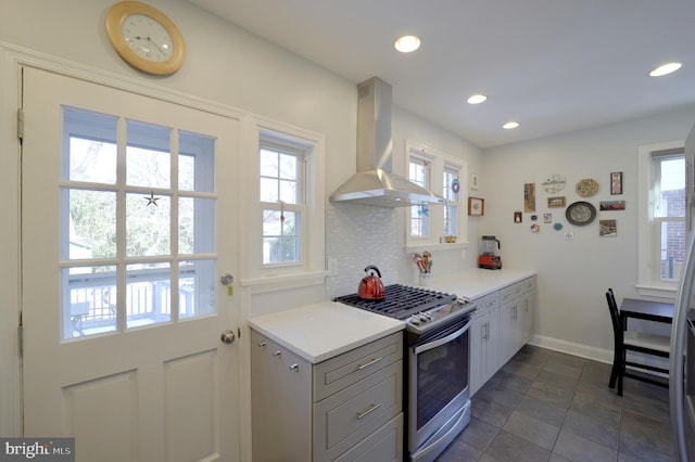 kitchen with extractor fan, dark tile patterned flooring, backsplash, and stainless steel gas range