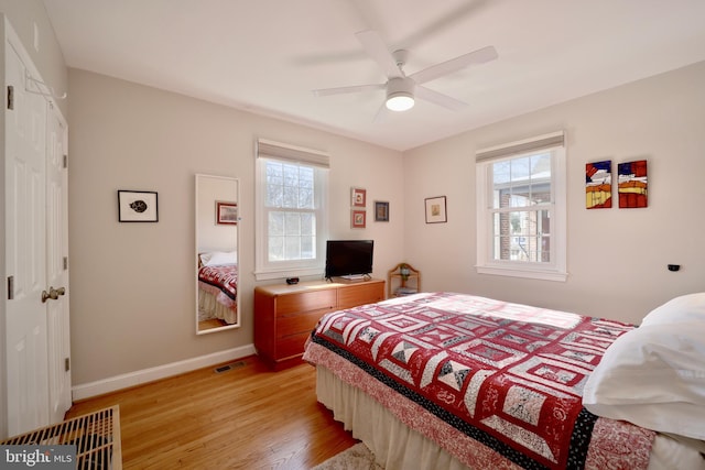 bedroom featuring ceiling fan, light hardwood / wood-style floors, and multiple windows