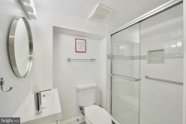 bathroom with toilet, vanity, and a shower with shower door