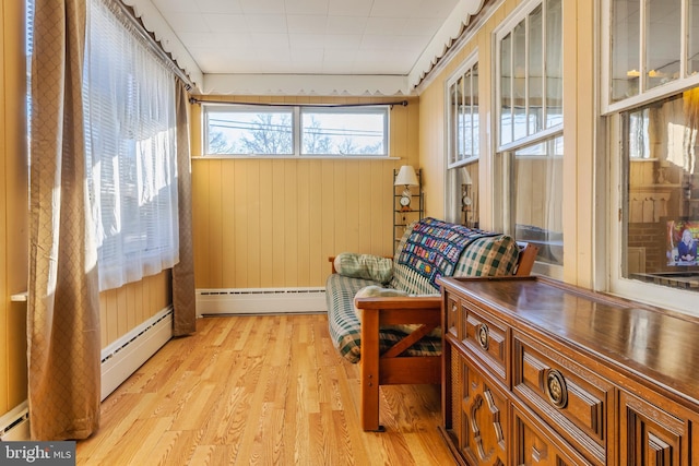 living area featuring baseboard heating, wood walls, and light hardwood / wood-style flooring