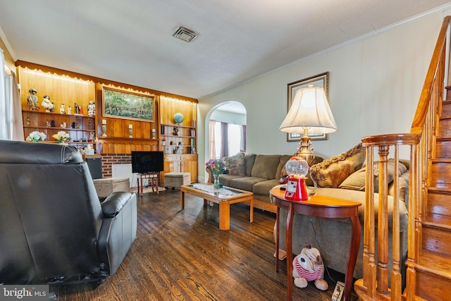 living room with dark wood-type flooring, crown molding, and built in features