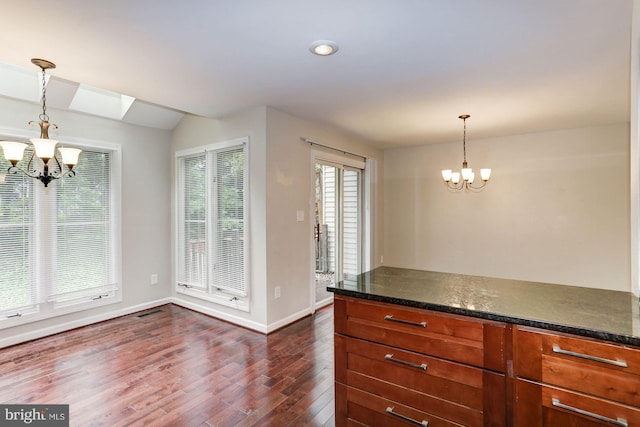 kitchen with pendant lighting, dark hardwood / wood-style floors, a skylight, and a notable chandelier