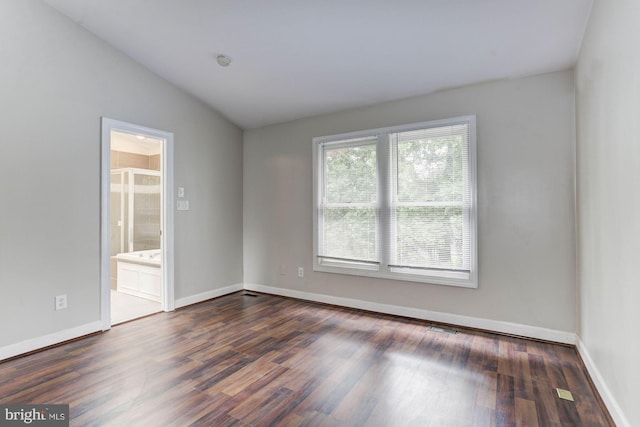 spare room with dark hardwood / wood-style floors and vaulted ceiling