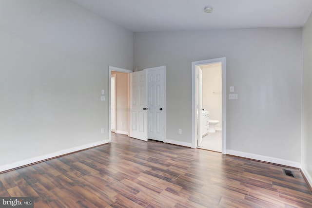 empty room with dark hardwood / wood-style floors and vaulted ceiling