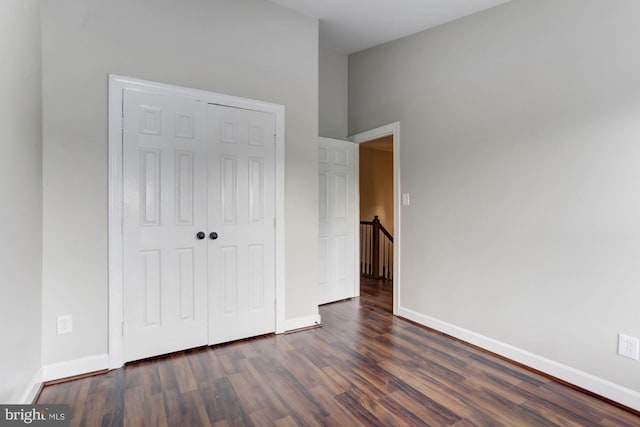 unfurnished bedroom with dark hardwood / wood-style flooring and a closet