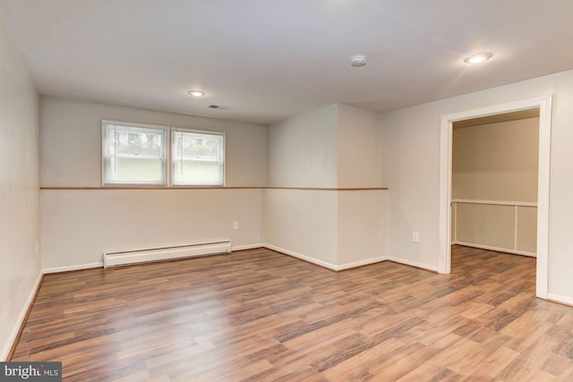 spare room featuring wood-type flooring and a baseboard radiator