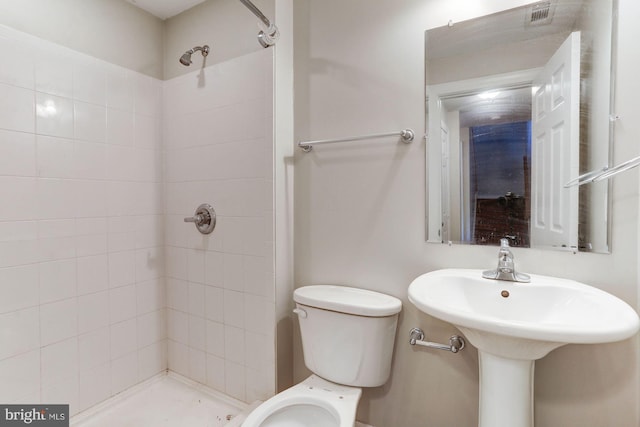 bathroom featuring tiled shower and toilet