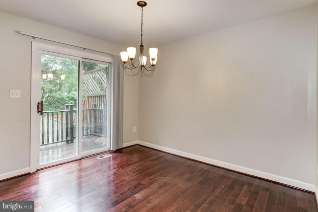 spare room with dark hardwood / wood-style floors and a notable chandelier