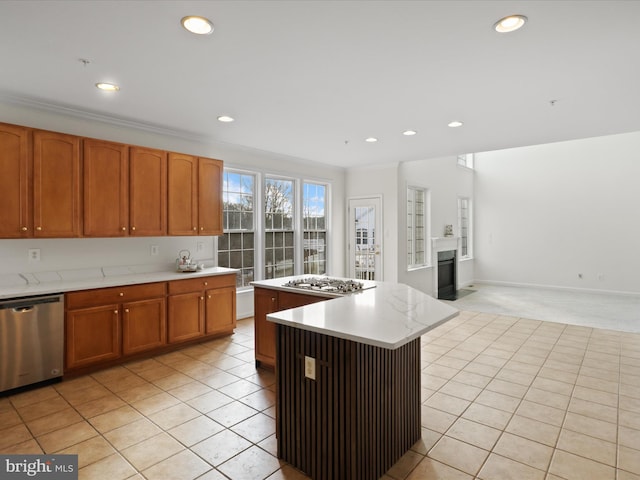 kitchen featuring a kitchen island, stainless steel appliances, light colored carpet, and ornamental molding