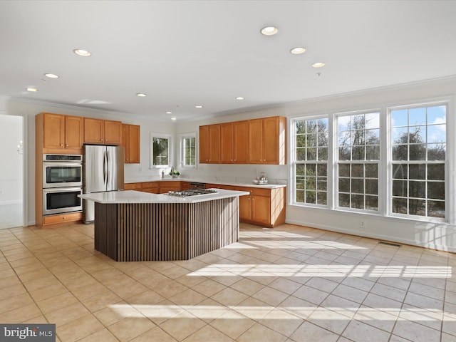 kitchen featuring a kitchen island, light tile patterned floors, crown molding, and appliances with stainless steel finishes