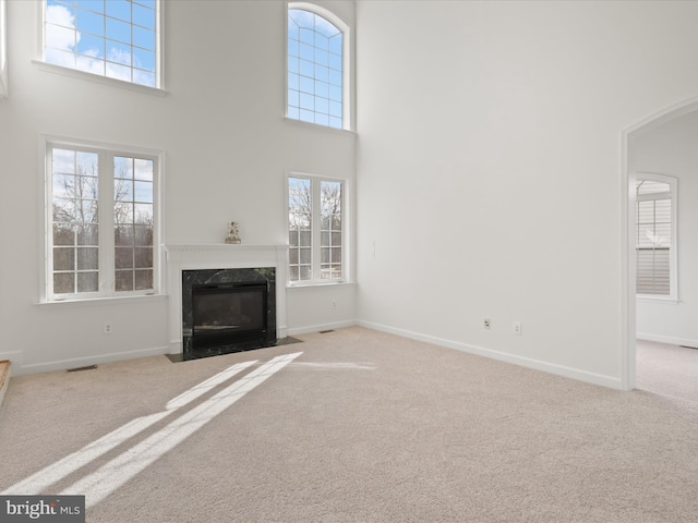 unfurnished living room featuring a high ceiling, light colored carpet, and a fireplace