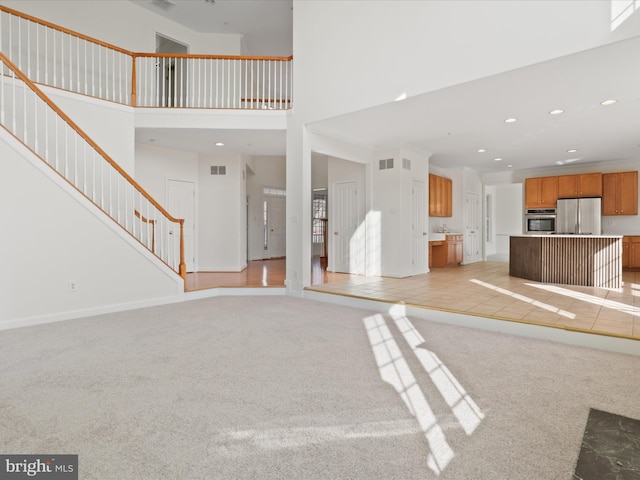 unfurnished living room with a high ceiling and light colored carpet