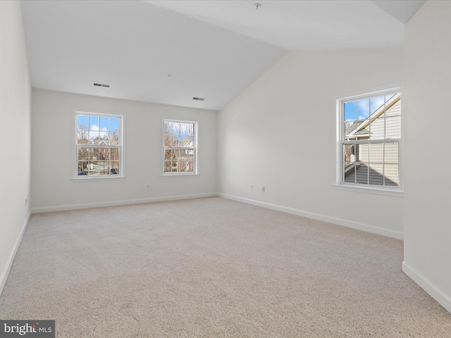 empty room with lofted ceiling, light carpet, and plenty of natural light